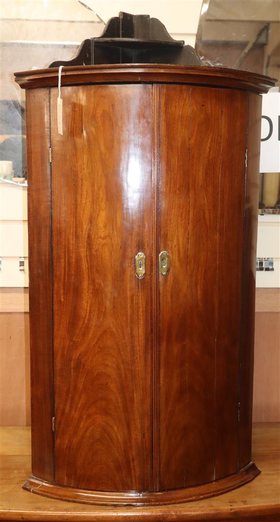 A George III mahogany bowfront hanging corner cabinet W.58cm